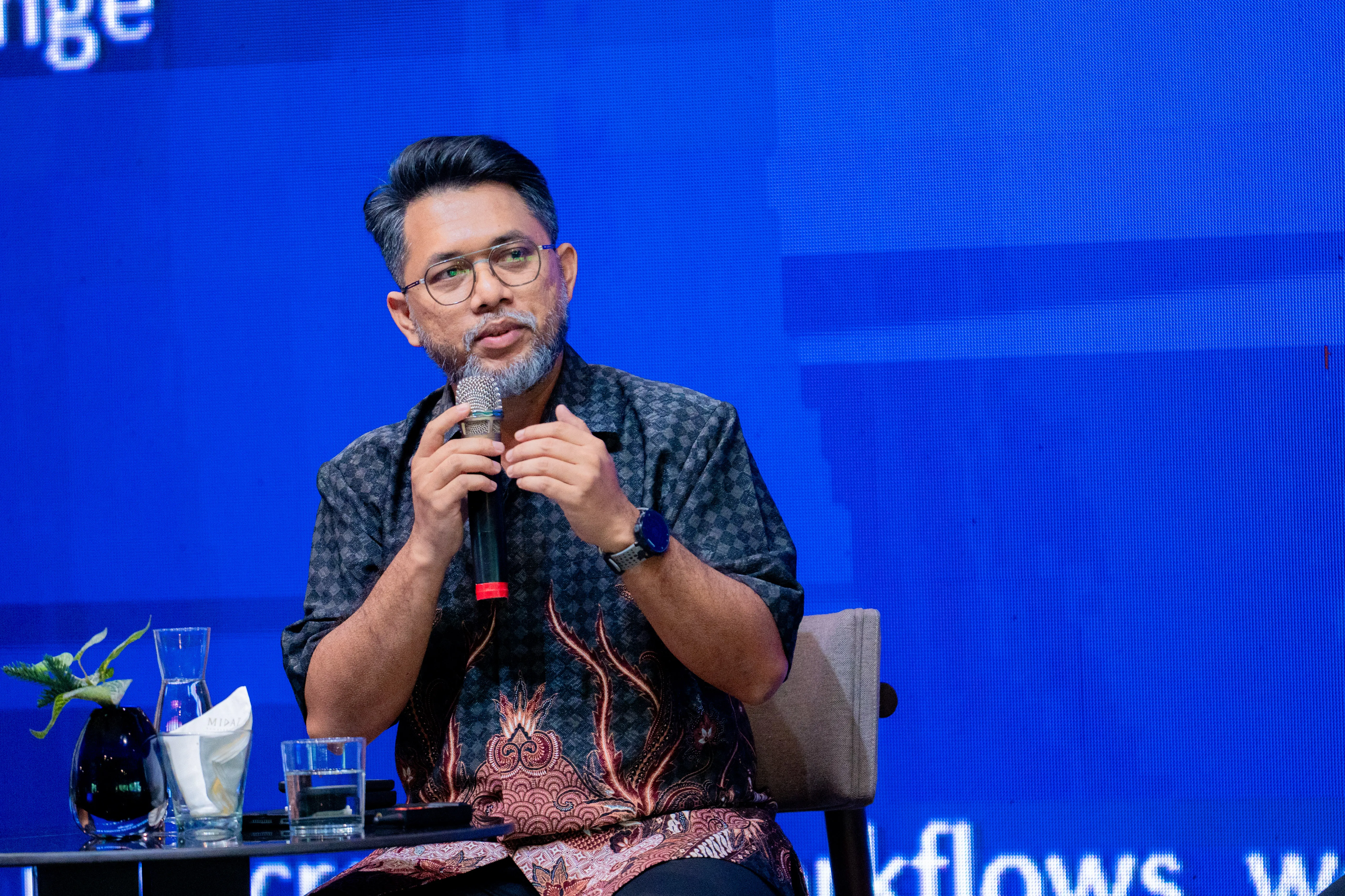 Hazmi speaking into a microphone and gesturing during the MMA panel.